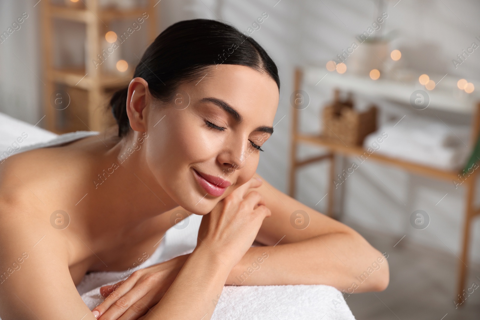 Photo of Beautiful happy woman relaxing on massage table in spa salon