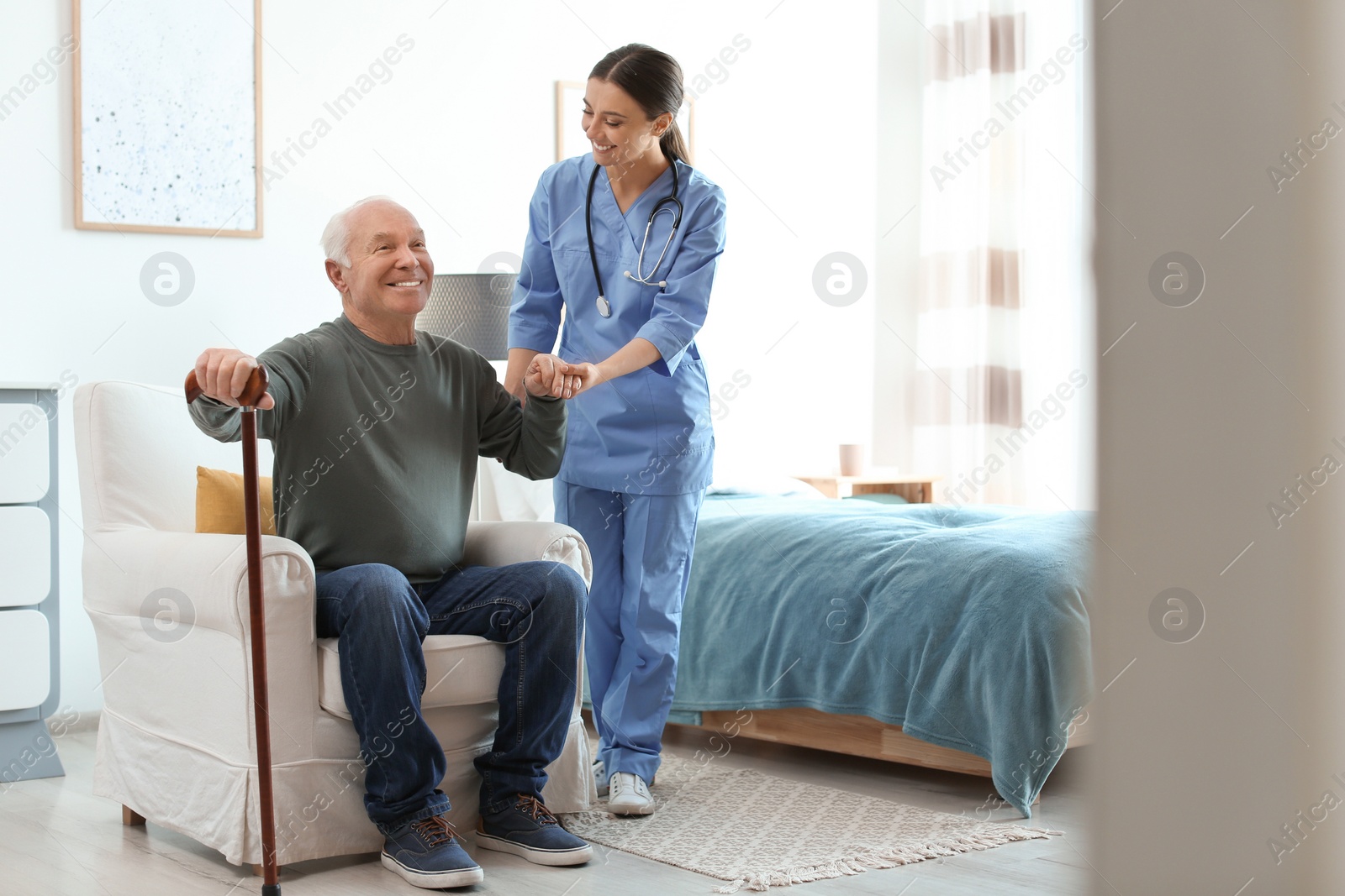 Photo of Care worker helping elderly man with stick in geriatric hospice