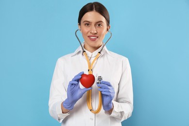 Photo of Doctor with stethoscope and red heart on light blue background. Cardiology concept