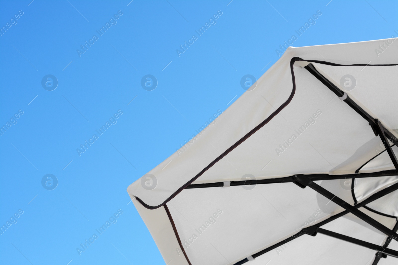 Photo of Beautiful white beach umbrella against blue sky. Space for text