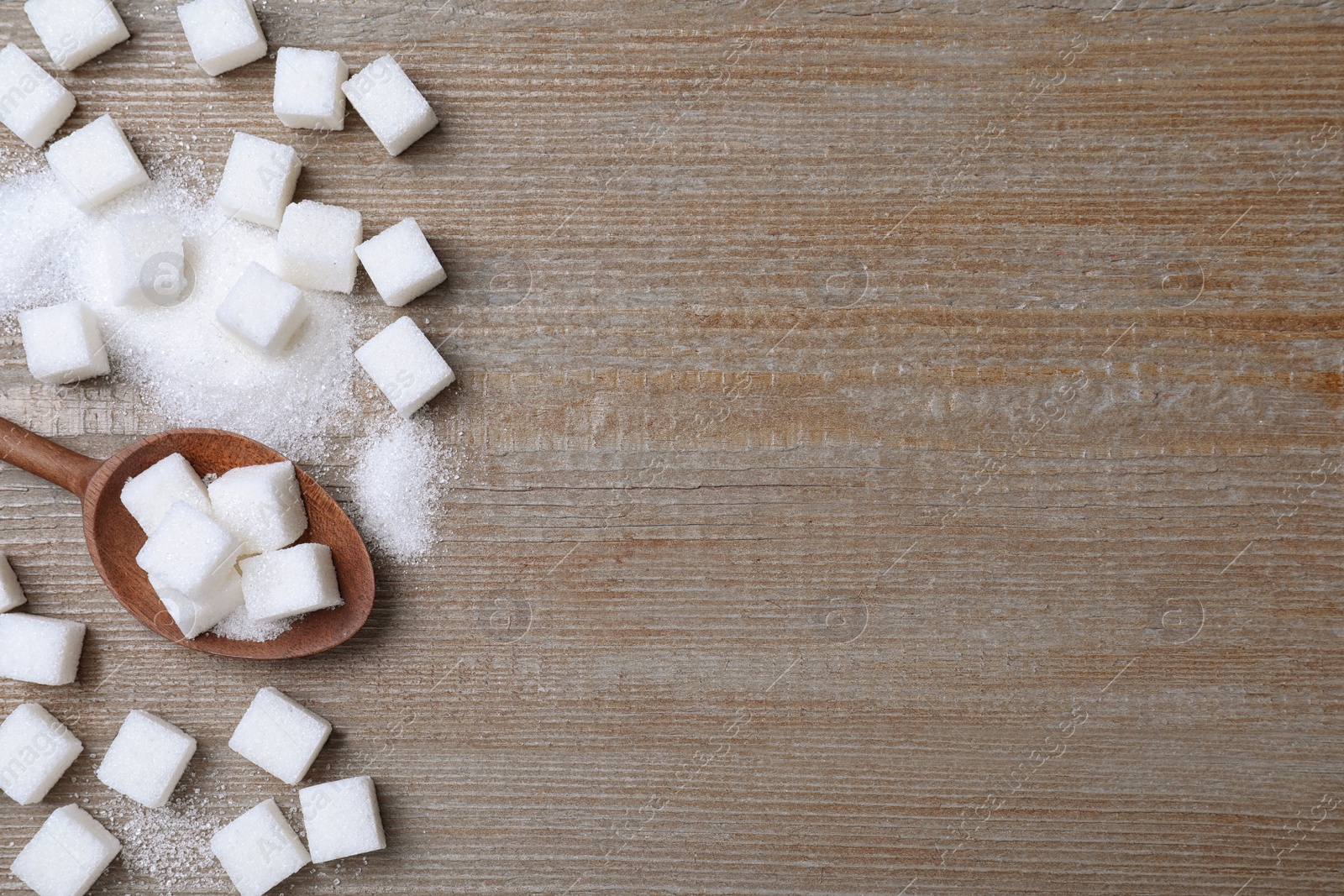 Photo of Refined sugar on wooden table, flat lay. Space for text