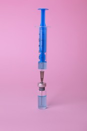 Photo of Disposable syringe with needle and vial on pink background