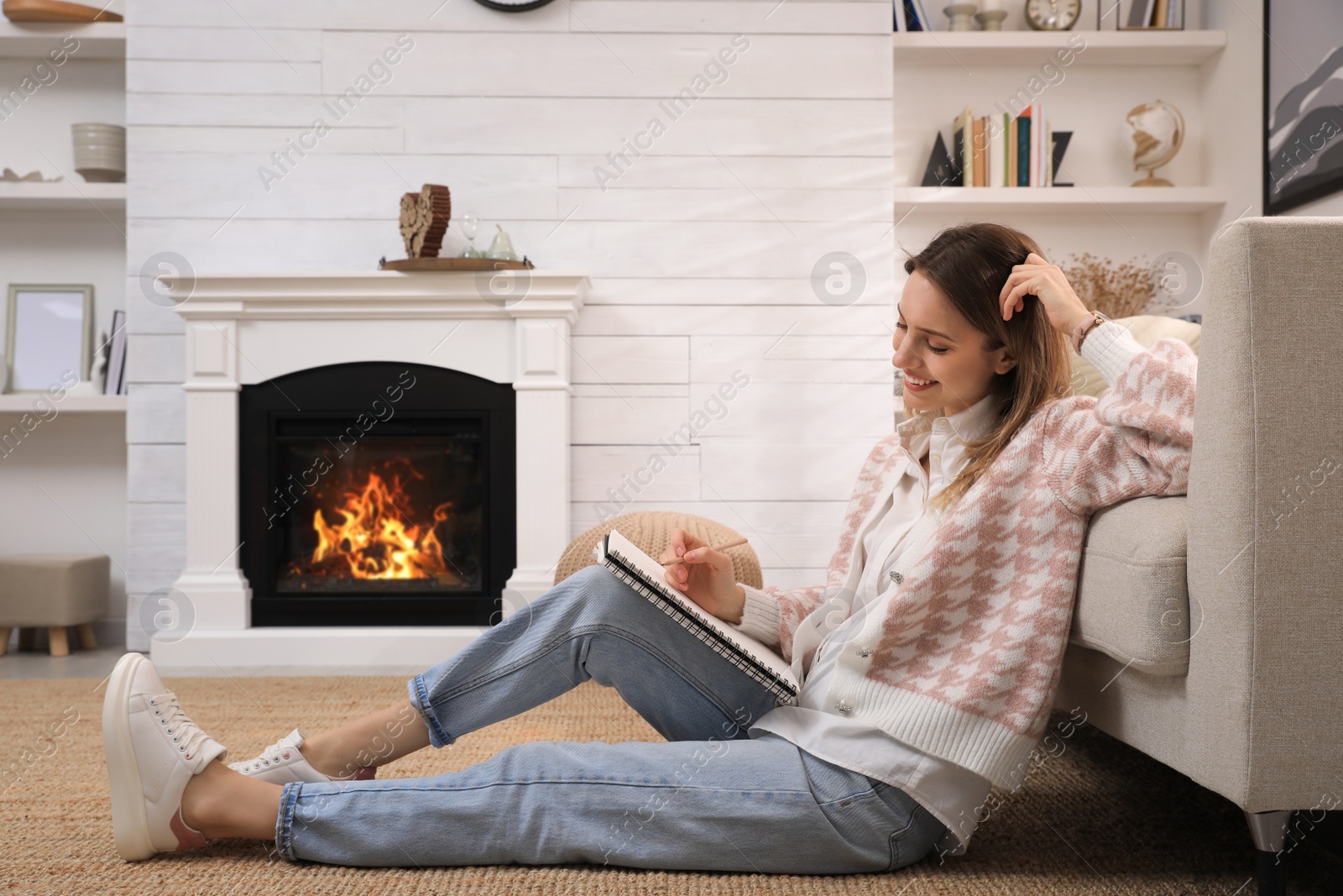 Photo of Young woman drawing in sketchbook with pencil at home, space for text