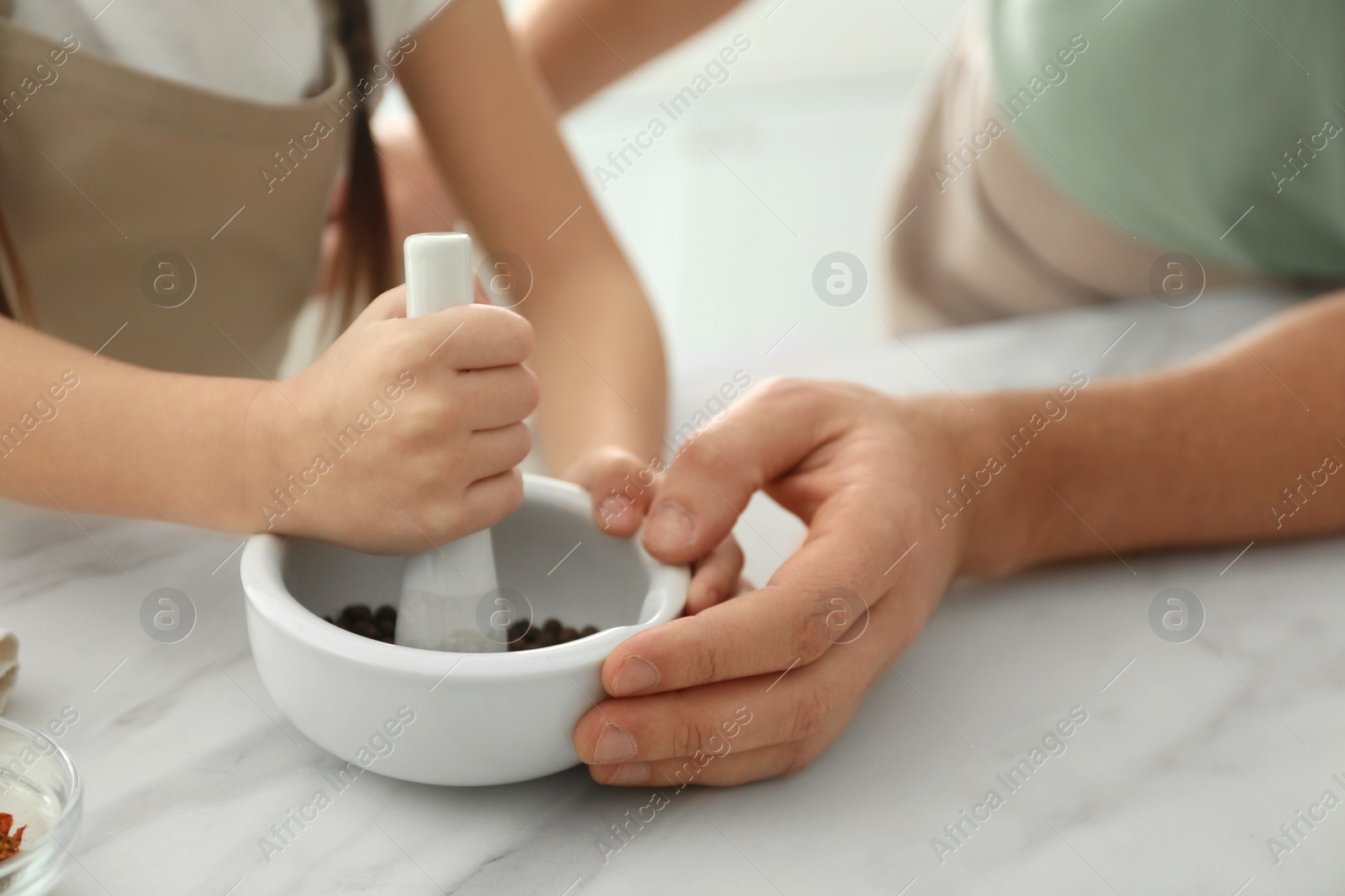 Photo of Father and daughter pounding pepper in kitchen, closeup. Cooking together