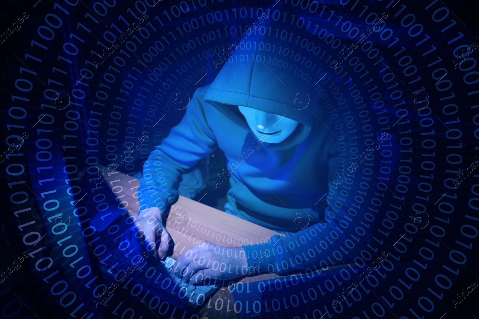 Image of Anonymous man in mask with computer and binary code in darkness
