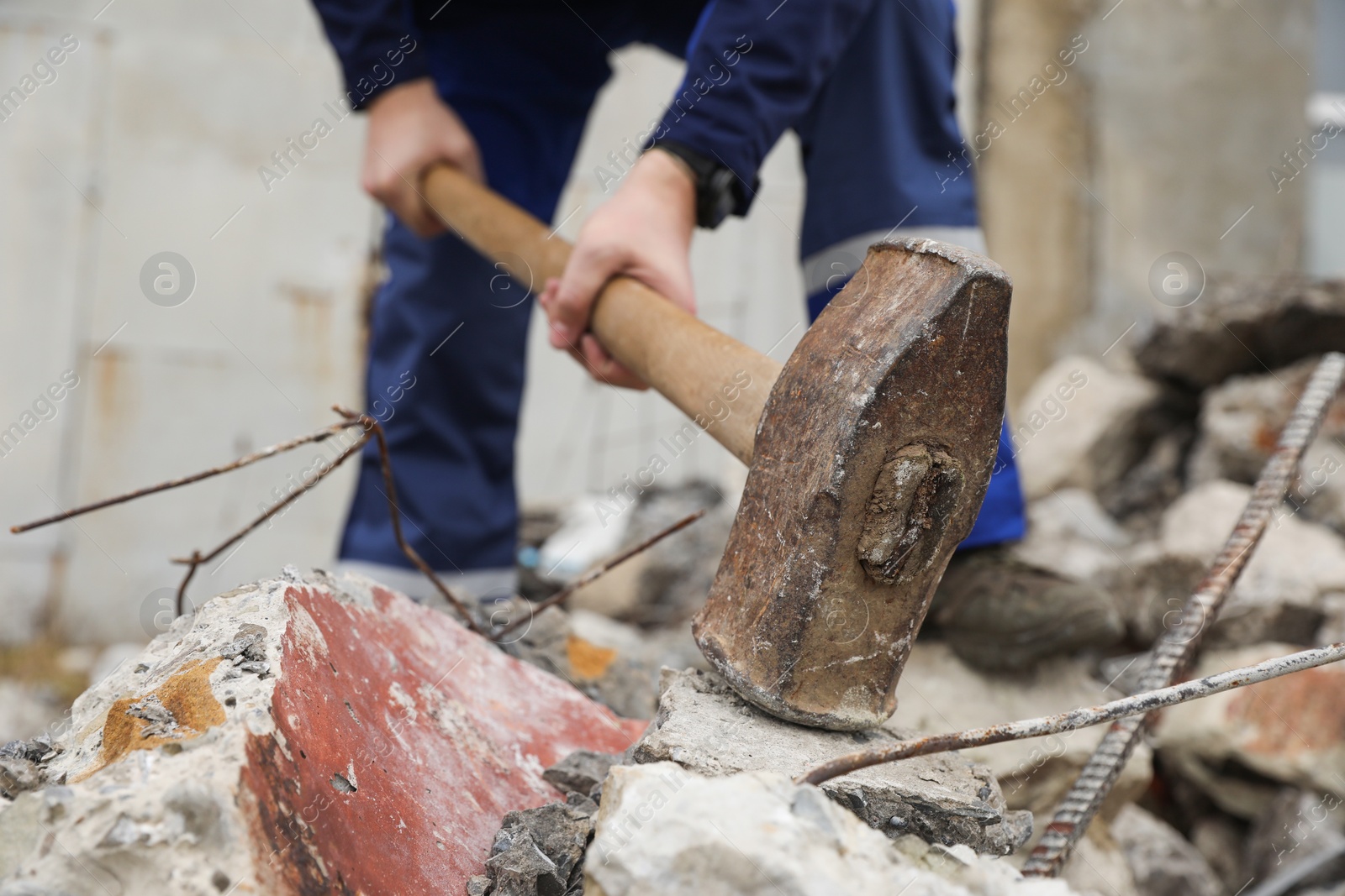 Photo of Man breaking stones with sledgehammer outdoors, selective focus