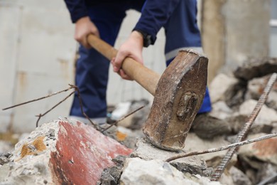 Photo of Man breaking stones with sledgehammer outdoors, selective focus