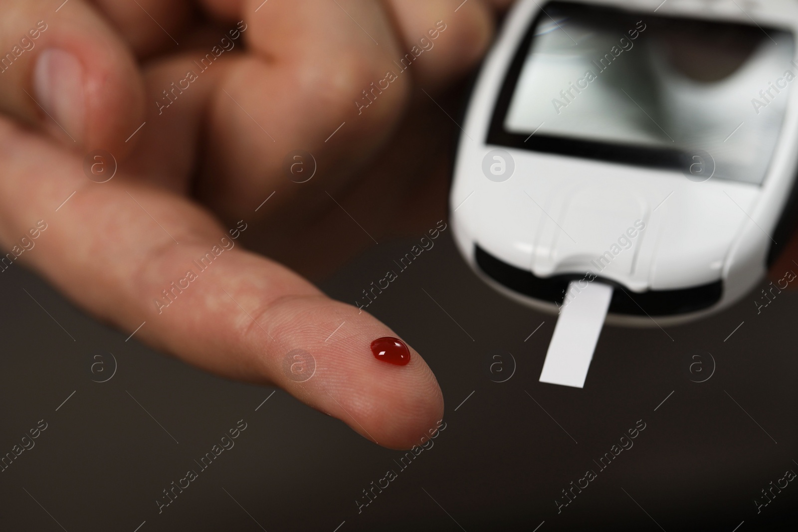 Photo of Diabetes test. Man checking blood sugar level with glucometer on blurred background, closeup