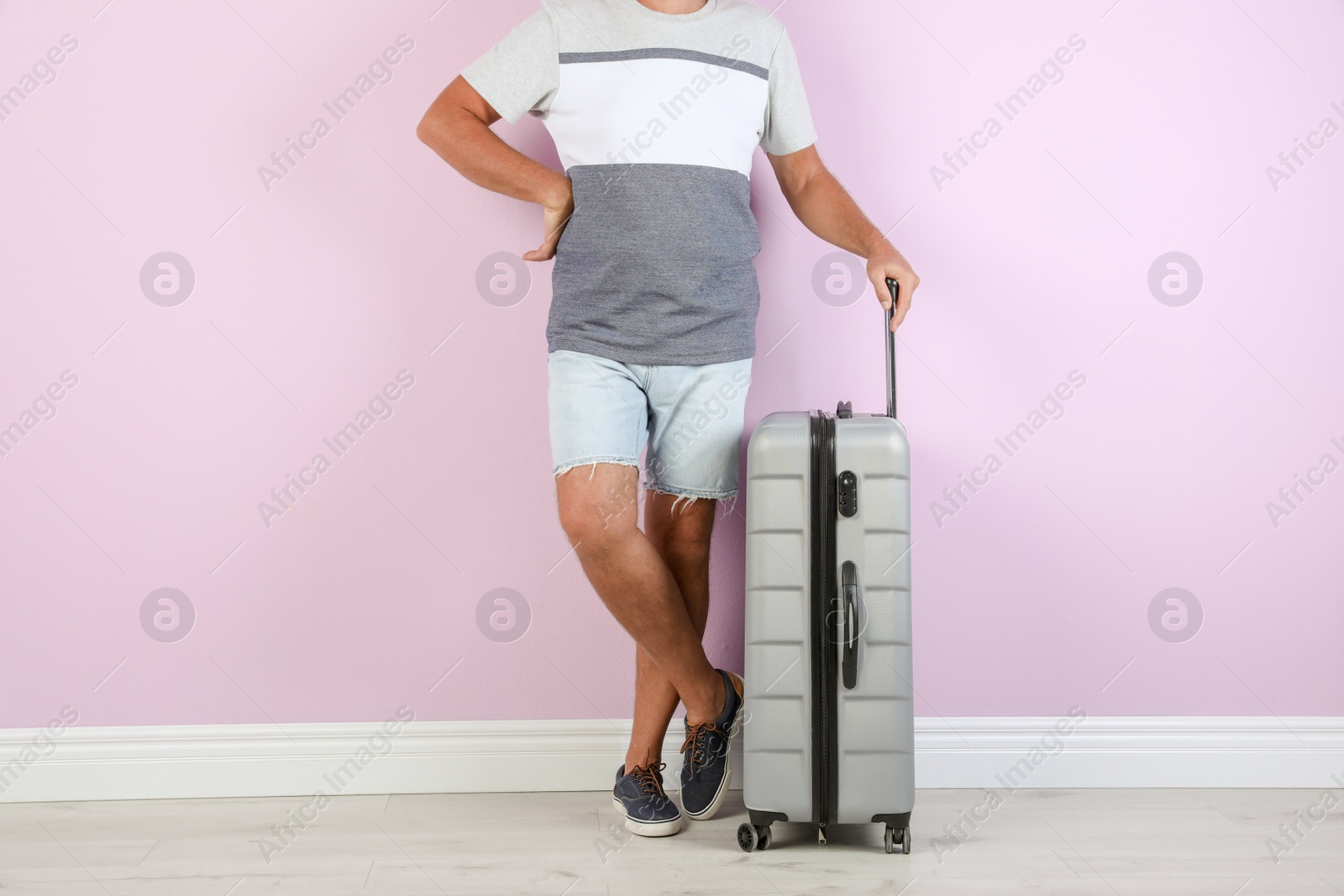 Photo of Senior man with suitcase near color wall. Vacation travel
