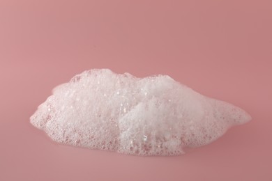Photo of Fluffy bath foam on pink background, closeup. Care product