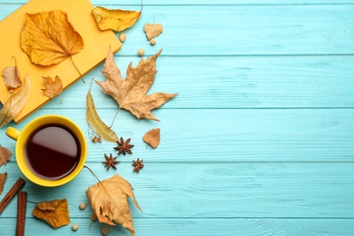 Photo of Flat lay composition with cup of hot drink and autumn leaves on light blue wooden table, space for text. Cozy atmosphere