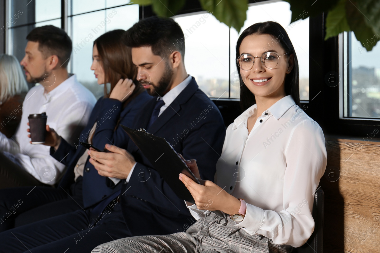 Photo of Young woman with clipboard waiting for job interview in office hall