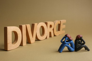 Photo of Word Divorce made of wooden letters and plasticine people figures on beige background