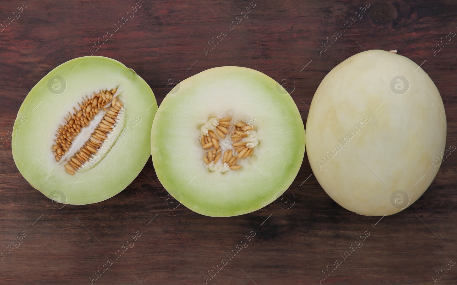 Photo of Cut and whole tasty ripe melons on wooden table, flat lay