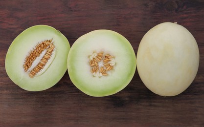 Photo of Cut and whole tasty ripe melons on wooden table, flat lay