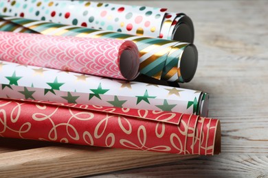 Photo of Different colorful wrapping paper rolls on white wooden table, closeup