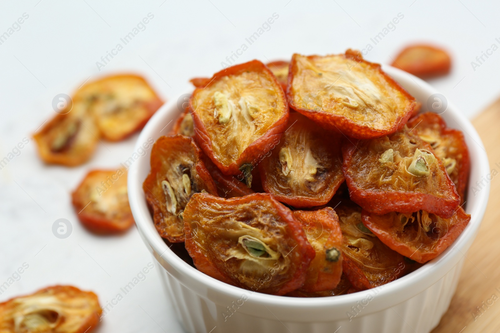 Photo of Bowl with cut dried kumquat fruits on table, closeup