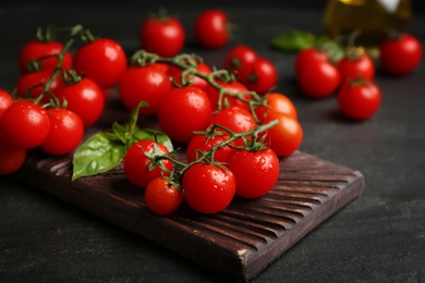 Photo of Fresh ripe cherry tomatoes with water drops on black table