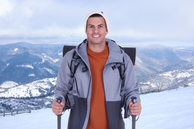 Image of Man with backpack and trekking poles in snowy mountains