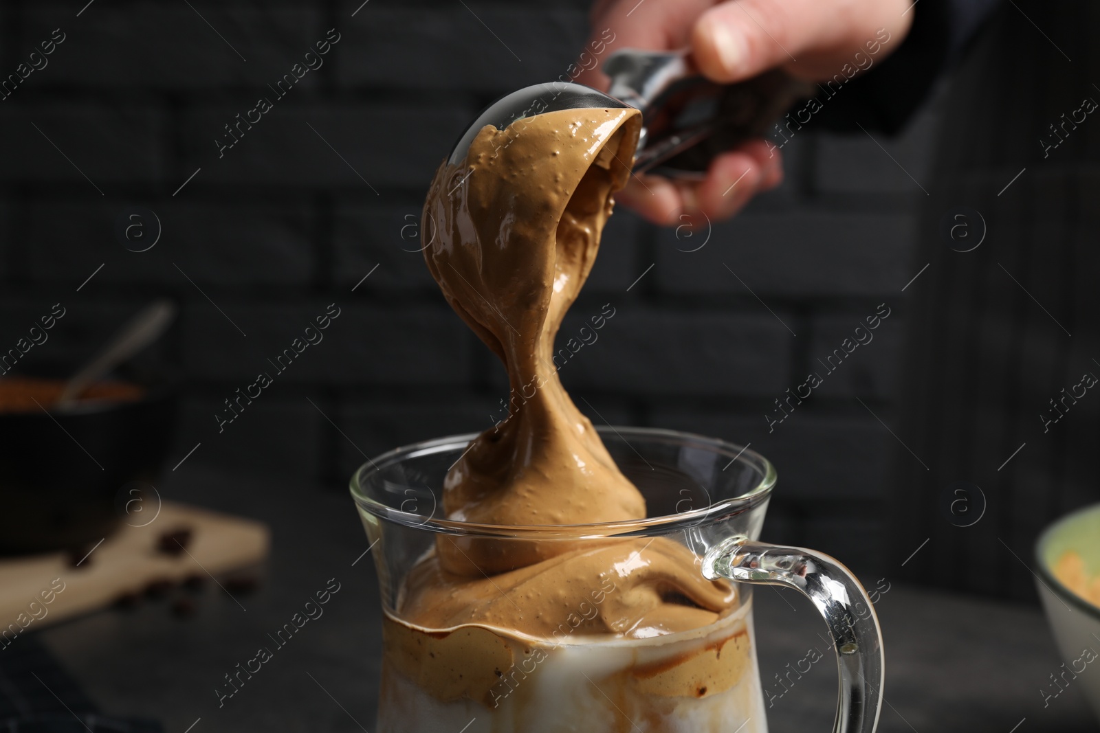 Photo of Woman making dalgona coffee indoors, closeup view