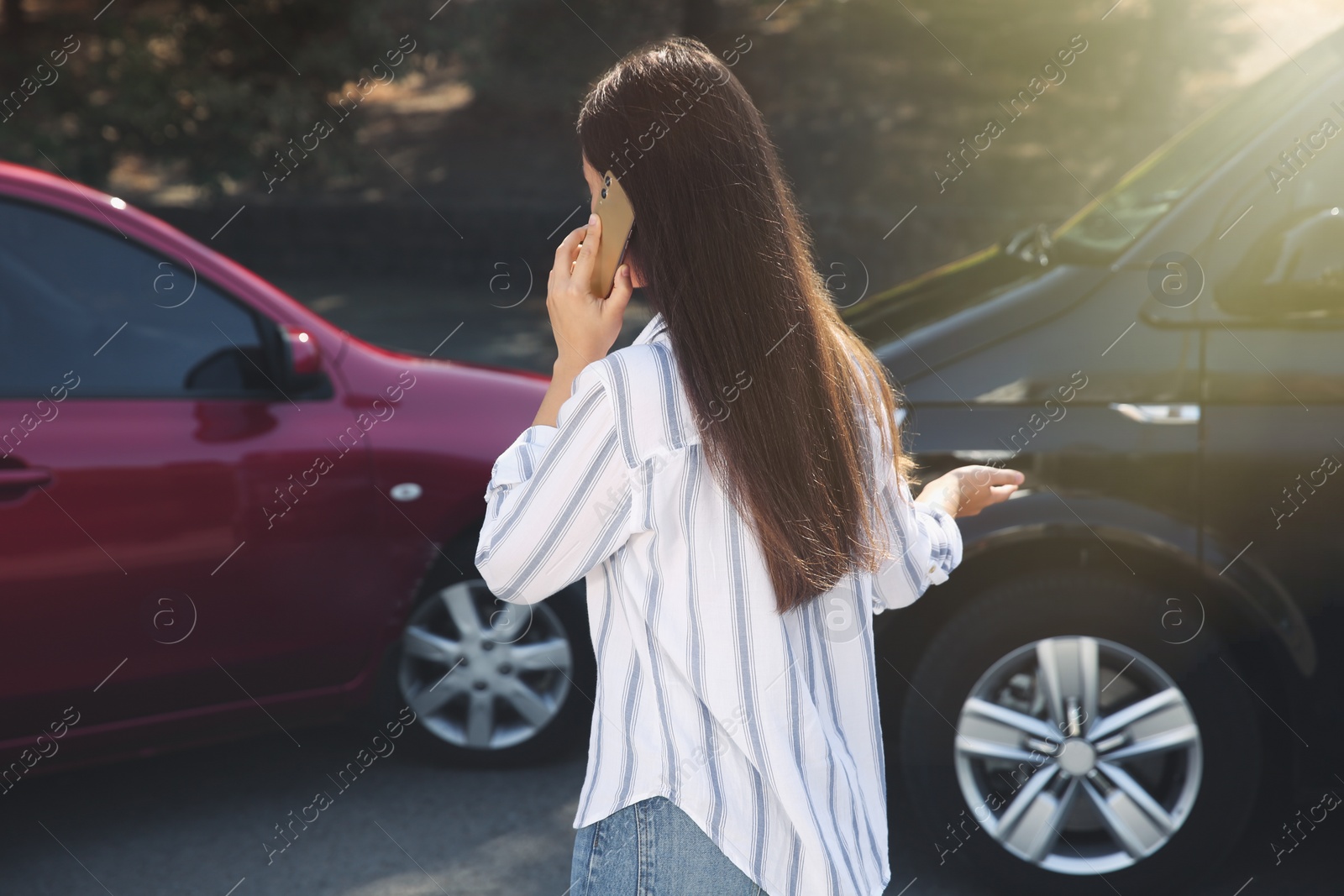 Photo of Young woman talking on phone after car accident outdoors, back view