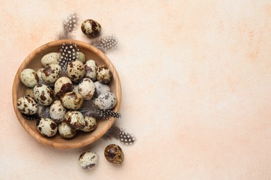 Photo of Speckled quail eggs and feathers on beige background, flat lay. Space for text