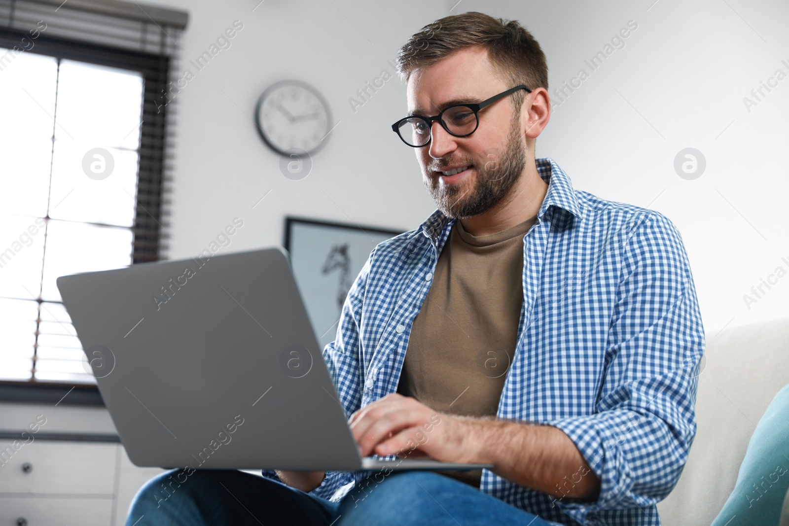 Photo of Young man using laptop in living room