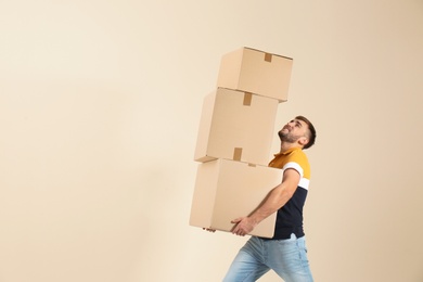 Young man carrying carton boxes on color background. Posture concept