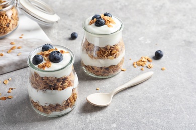 Photo of Jars with yogurt, berries and granola on  table