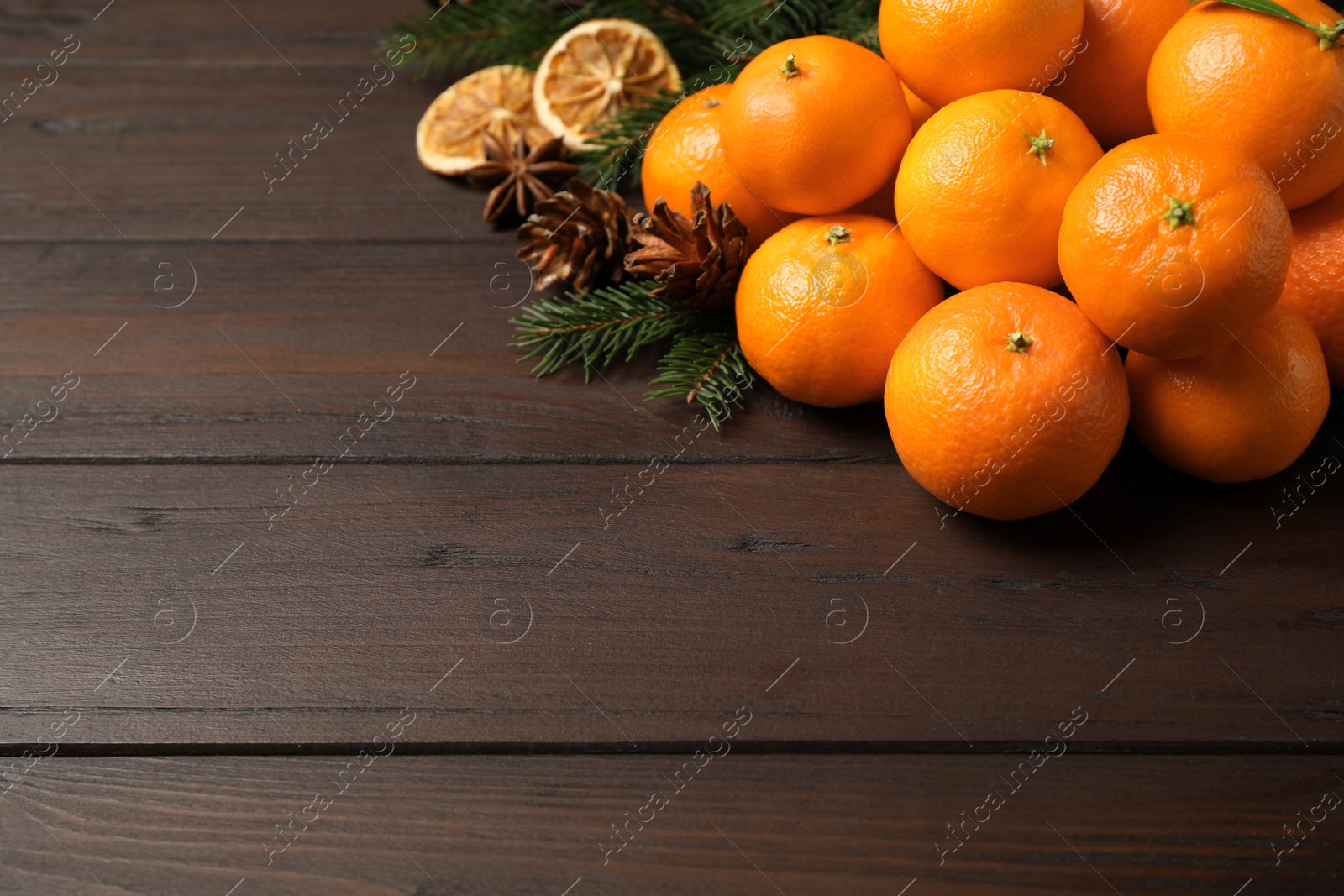 Photo of Christmas composition with fresh tangerines and fir tree branches on wooden table, space for text