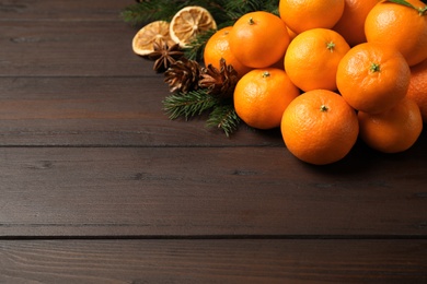 Photo of Christmas composition with fresh tangerines and fir tree branches on wooden table, space for text