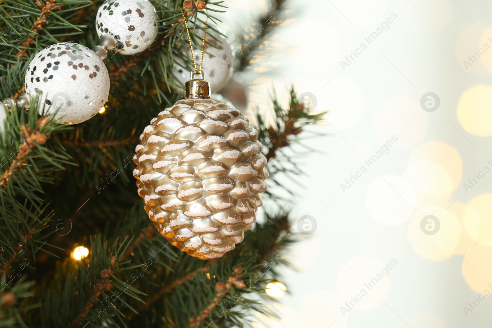 Photo of Cone shaped holiday bauble hanging on Christmas tree against blurred lights, closeup. Space for text