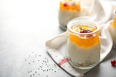 Photo of Creamy rice pudding with red currant, jam and oatmeal in jar on table. Space for text