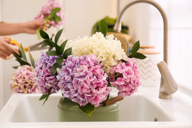 Photo of Closeup view of woman making bouquet, focus on beautiful hydrangea flowers in sink