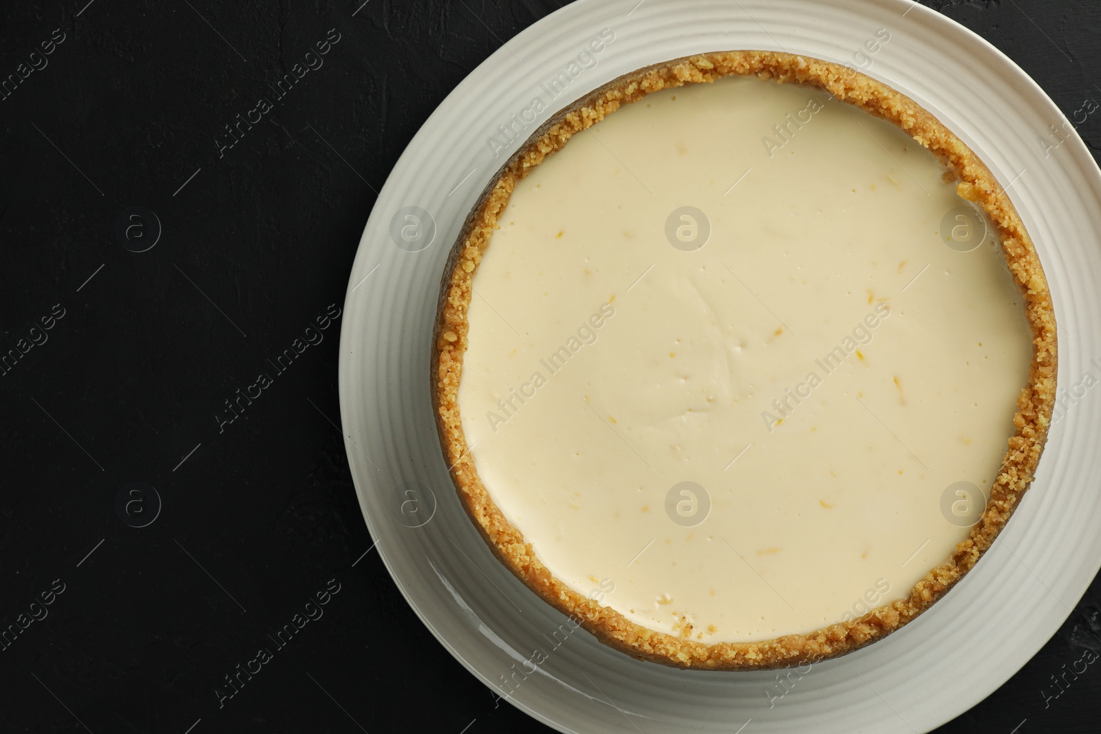 Photo of Tasty vegan tofu cheesecake on black table, top view. Space for text