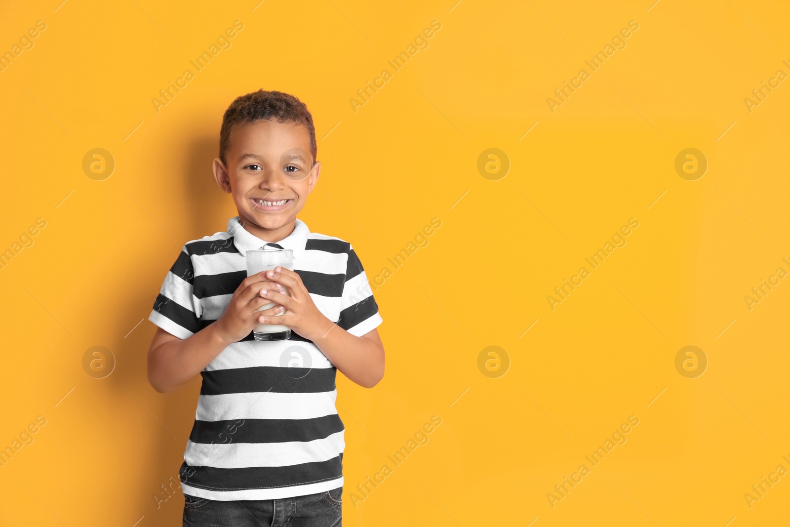 Photo of Adorable African-American boy with glass of milk on color background