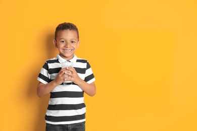 Photo of Adorable African-American boy with glass of milk on color background