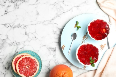 Flat lay composition with grapefruit jelly in bowls on marble table. Space for text