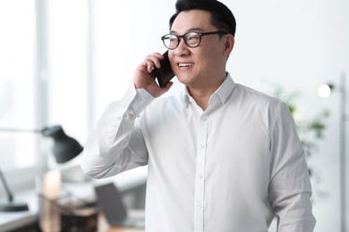 Photo of Portrait of smiling businessman talking by smartphone in office