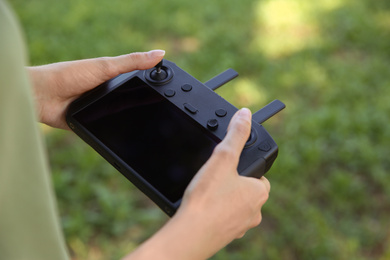 Woman holding new modern drone controller outdoors, closeup of hands