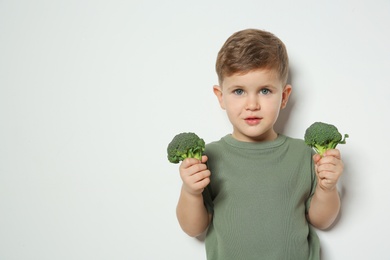 Photo of Adorable little boy with broccoli on white background. Space for text
