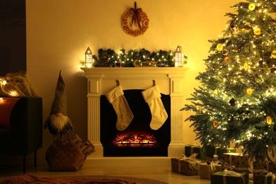 Photo of Stylish fireplace near decorated Christmas tree and accessories in cosy room