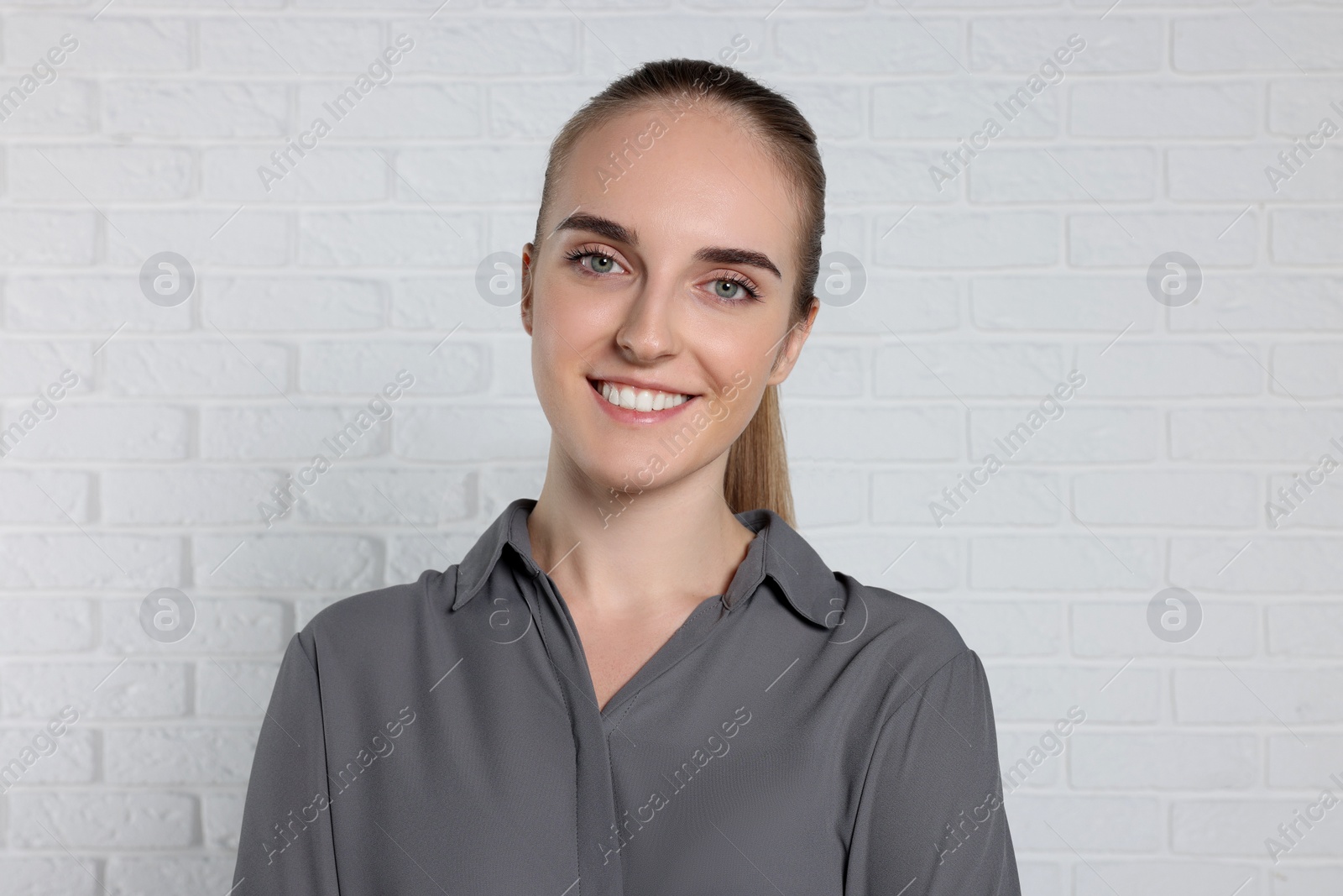 Photo of Portrait of happy young secretary near white brick wall