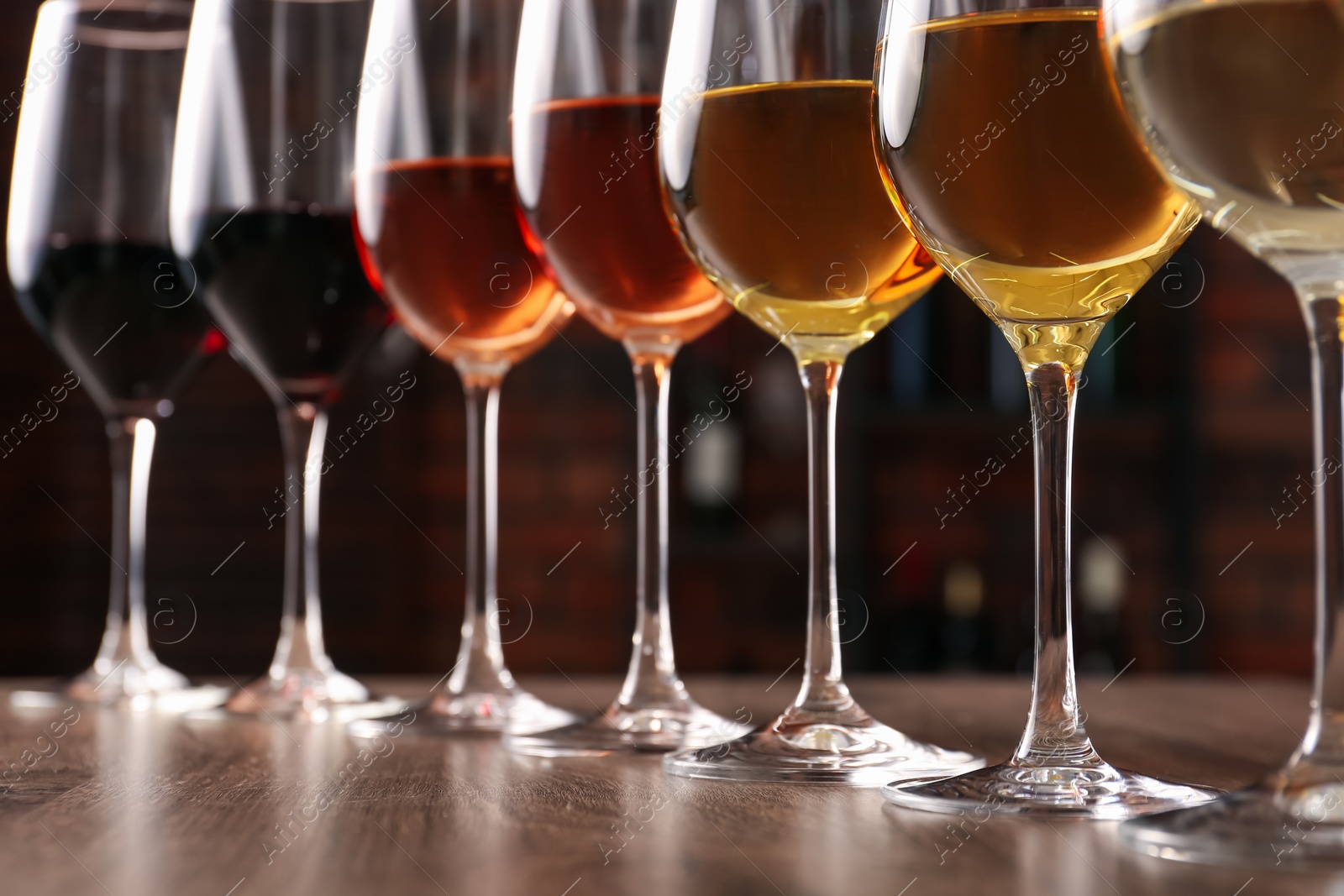 Photo of Different tasty wines in glasses on wooden table