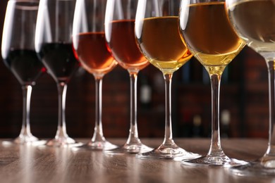 Different tasty wines in glasses on wooden table