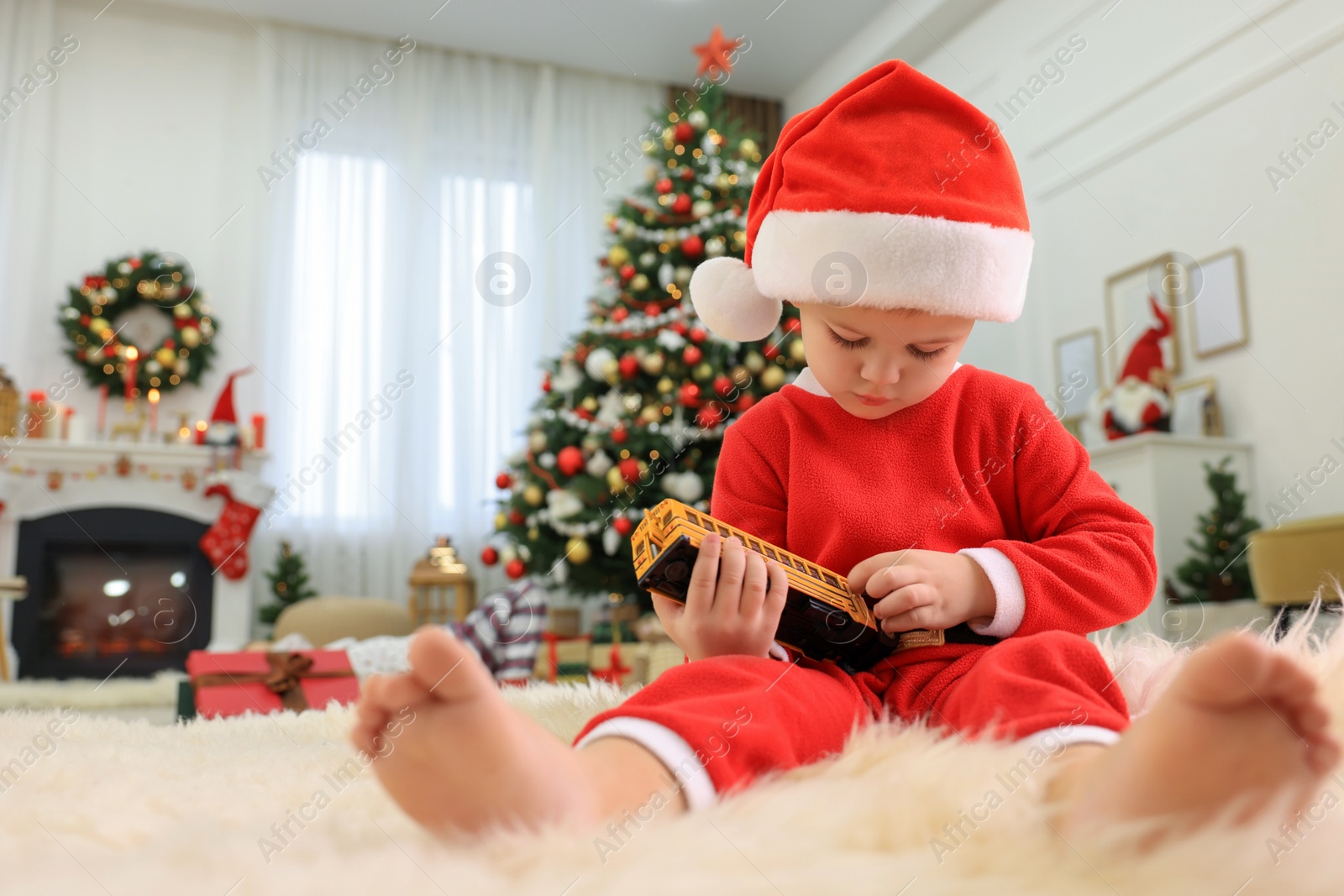 Photo of Cute little boy with toy car in room decorated for Christmas, low angle view