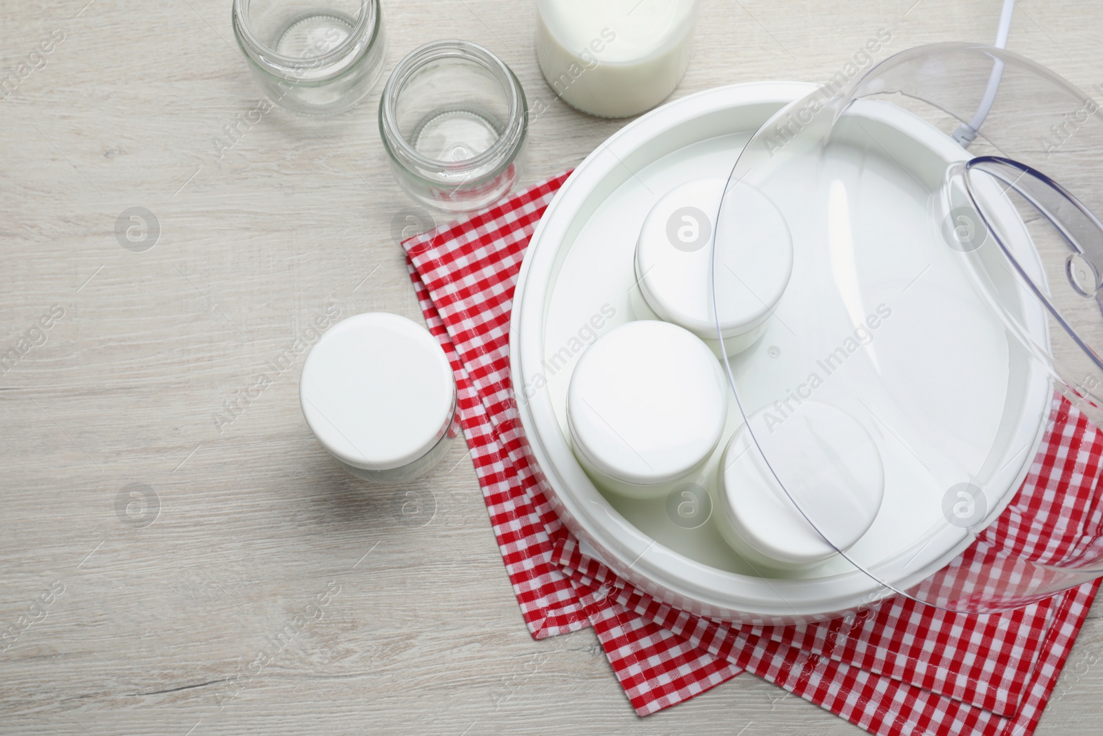Photo of Modern yogurt maker and jars on wooden table, flat lay