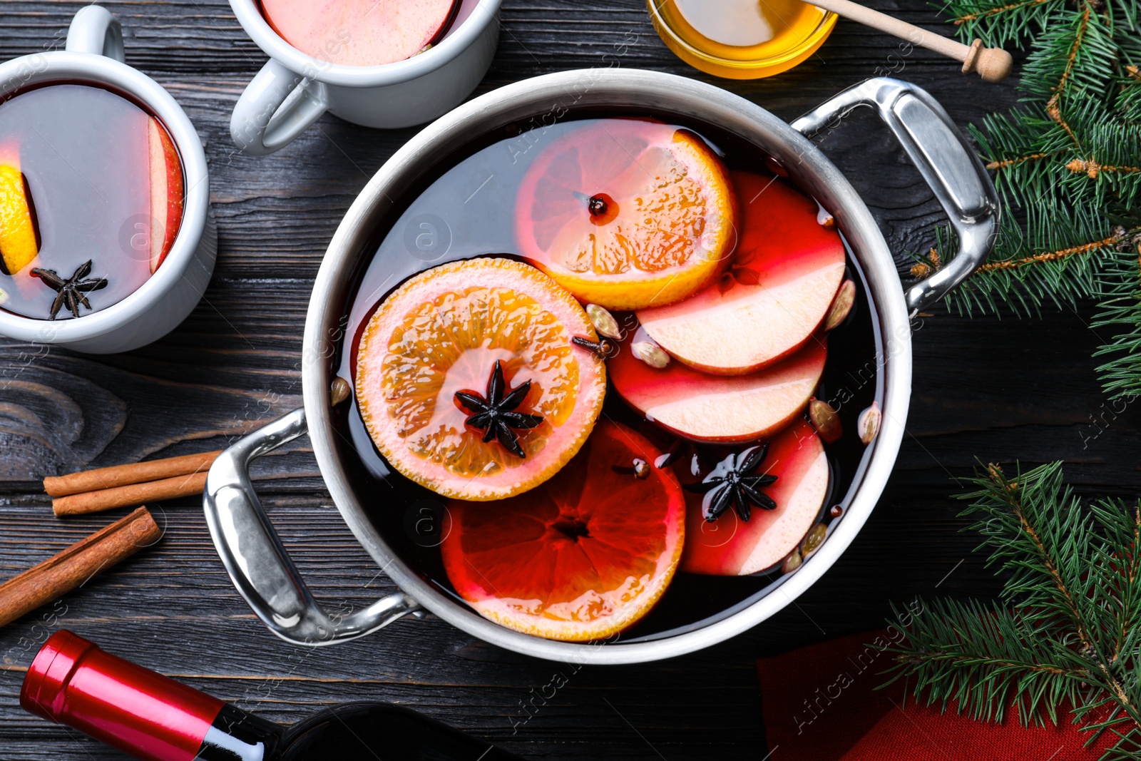 Photo of Delicious mulled wine and ingredients on black wooden table, flat lay