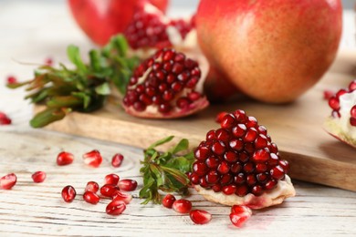 Photo of Delicious ripe pomegranates on white wooden table, closeup