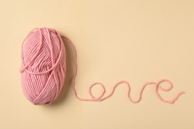 Word Love made with pink thread and woolen yarn on beige background, top view. Space for text